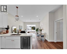 A modern kitchen with white cabinets and a wooden floor.