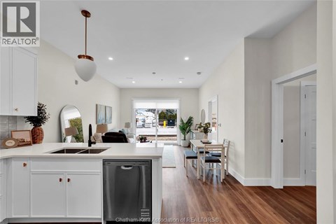 A modern kitchen with white cabinets and a wooden floor.