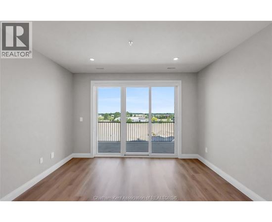 A large empty room with a sliding glass door leading to a balcony.