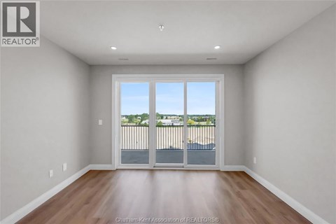 A large empty room with a sliding glass door leading to a balcony.
