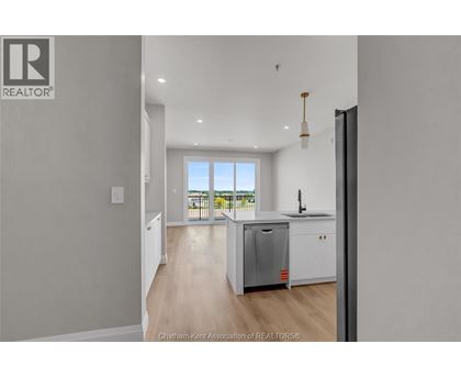 A kitchen with a refrigerator, sink, and a window overlooking a balcony.