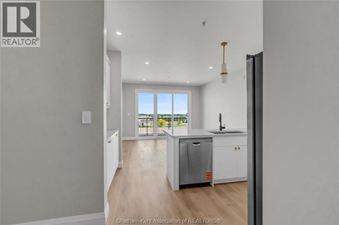 A kitchen with a refrigerator, sink, and a window overlooking a balcony.