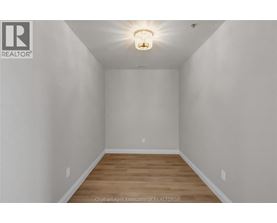 A white room with a light on the ceiling and wooden flooring.