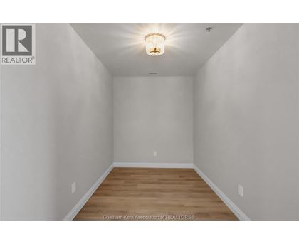 A white room with a light on the ceiling and wooden flooring.