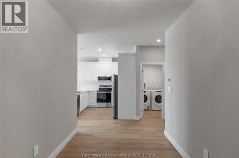 A well-lit, empty kitchen and living room with a washer and dryer in the laundry area.
