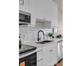 A kitchen with white cabinets and a black dishwasher.