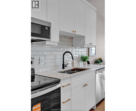 A kitchen with white cabinets and a black dishwasher.