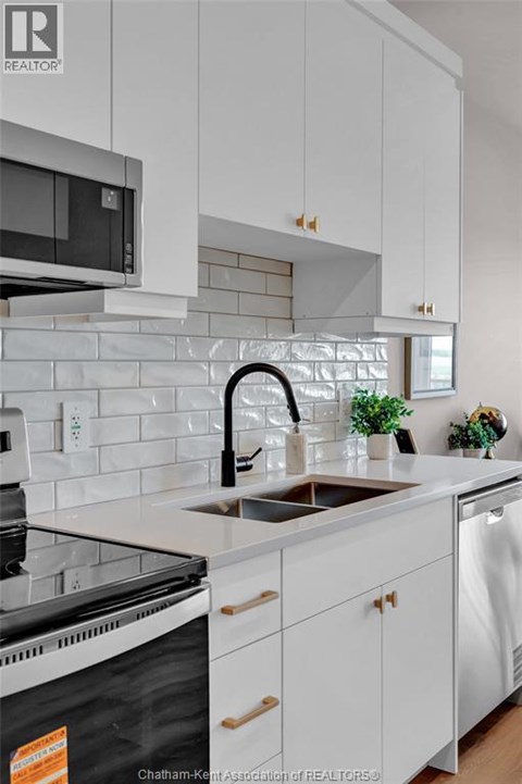 A kitchen with white cabinets and a black dishwasher.
