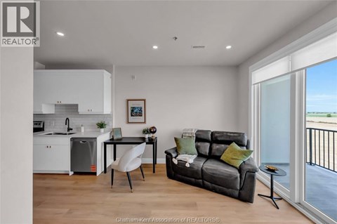 A modern living room with a grey sofa and a dining table with chairs.
