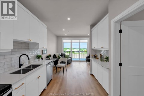 A modern kitchen with white cabinets and a large window.
