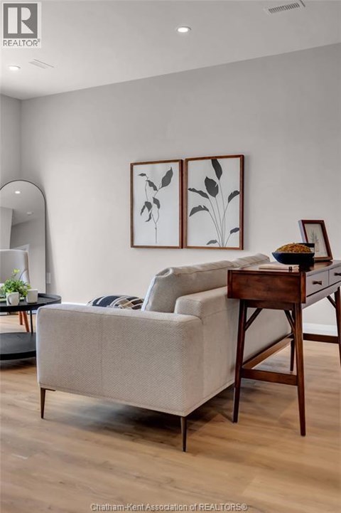 A living room with a couch, a chair, and a table with a plant on it.