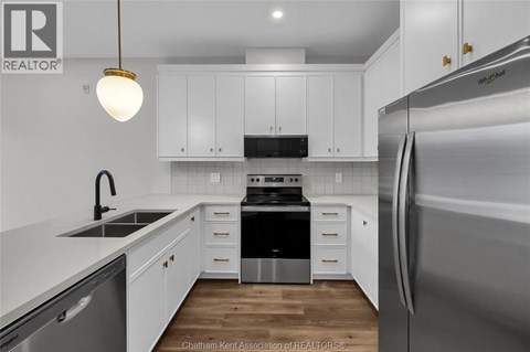 A kitchen with white cabinets and a stainless steel refrigerator.