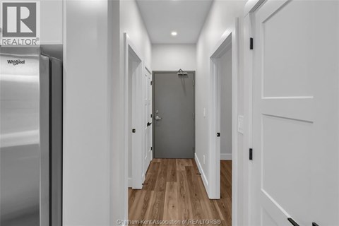 A hallway with a wooden floor and white walls.