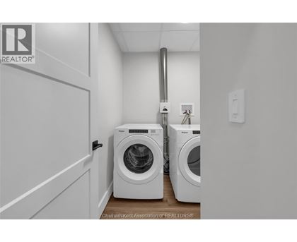 A laundry room with two washing machines and a door.