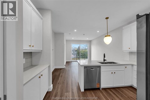 A modern kitchen with white cabinets and a wooden floor.