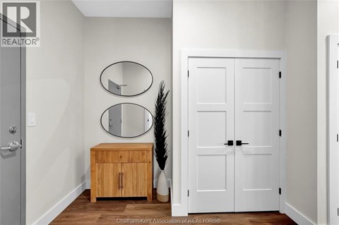A white door is in a room with a wooden cabinet and two mirrors.