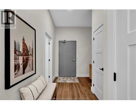 A room with a framed picture of a cityscape on the wall and a grey door in the middle.