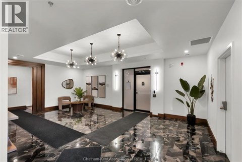A spacious lobby with a marble floor and a large chandelier.