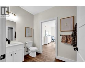 A white bathroom with wood floors and a white toilet.