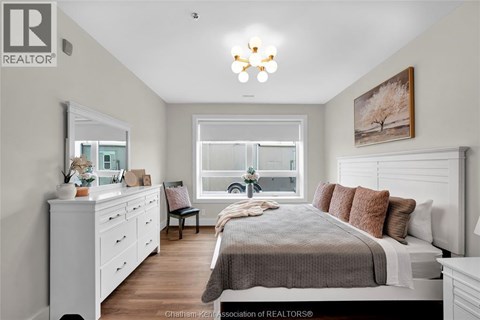 A well-lit bedroom with a large bed, a dresser, and a window.