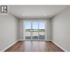A large empty room with a sliding glass door leading to a balcony.