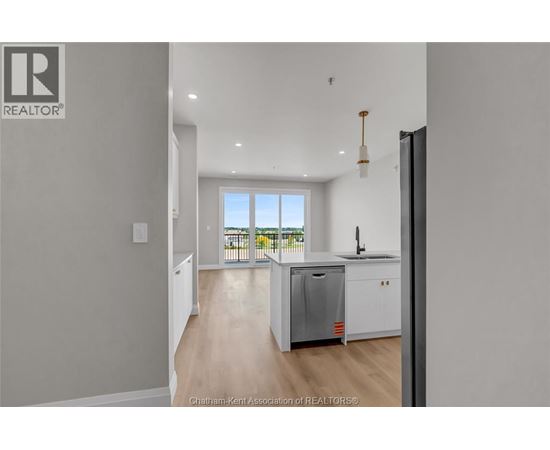 A kitchen with a refrigerator, sink, and a window overlooking a balcony.