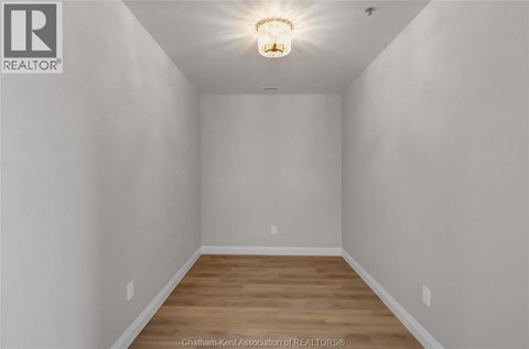A white room with a light on the ceiling and wooden flooring.