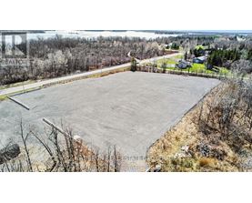 A large, empty parking lot sits in the foreground of a rural landscape.