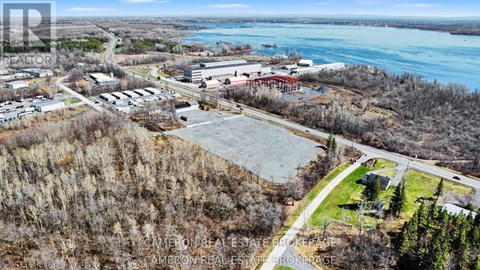 A real estate company is advertising a property with an aerial view of a parking lot, buildings, and a body of water.