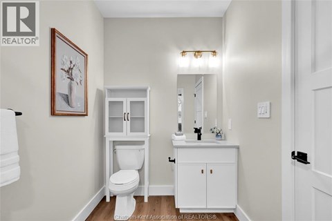 A white toilet sits in a bathroom next to a white cabinet.