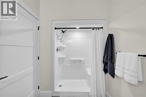 A white bathroom with a shower curtain and a towel hanging on the wall.