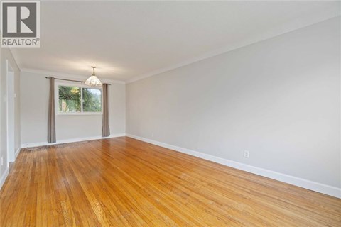 A room with wooden flooring and a window with curtains.