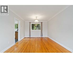 A room with wooden floors and a window with a view of trees.