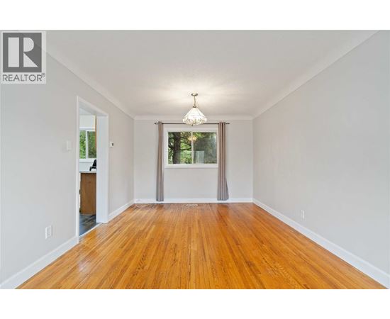 A room with wooden floors and a window with a view of trees.
