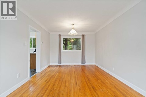 A room with wooden floors and a window with a view of trees.
