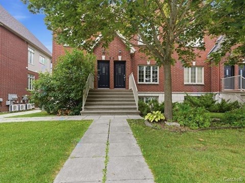 A red brick building with a black door and steps leading up to it.