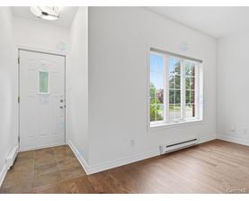 A room with a white door and a window with a view of trees outside.