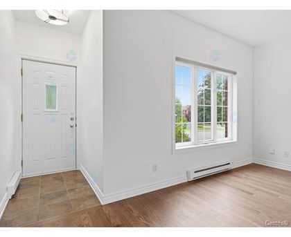 A room with a white door and a window with a view of trees outside.