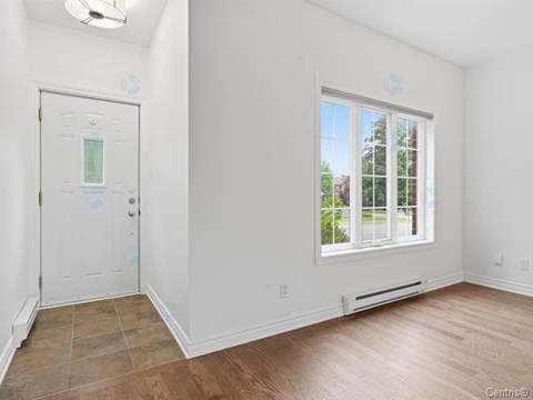 A room with a white door and a window with a view of trees outside.