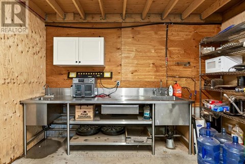 A kitchen area with a stainless steel table and a wooden wall.