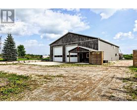 A large barn-like building with a gravel driveway in front.