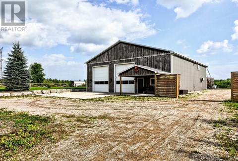 A large barn-like building with a gravel driveway in front.