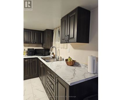 A kitchen with dark wood cabinets and marble countertops.
