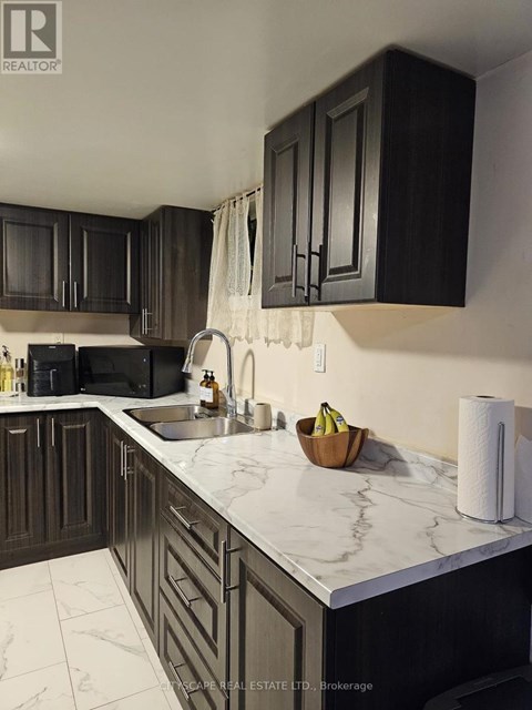 A kitchen with dark wood cabinets and marble countertops.