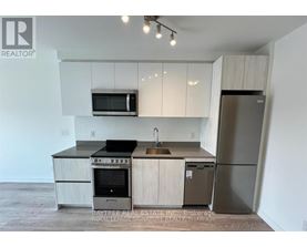 A kitchen with a refrigerator, oven, and microwave.