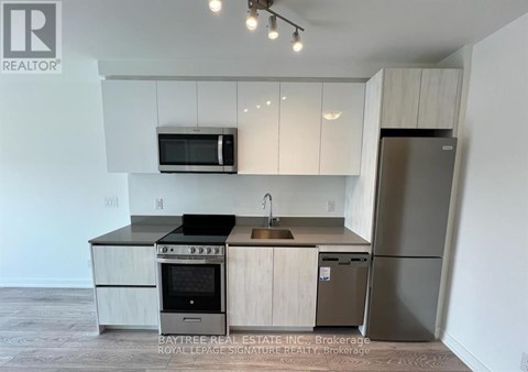 A kitchen with a refrigerator, oven, and microwave.