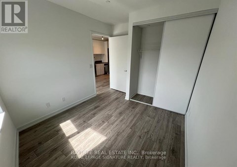 A real estate listing image of a room with wood flooring and white walls.