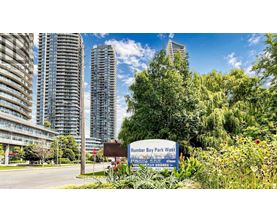 A sign for Humber Bay Park West stands in front of a row of tall buildings.