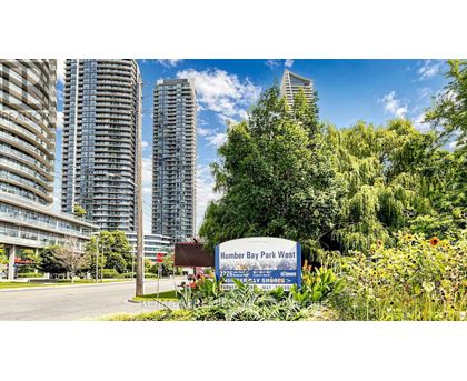 A sign for Humber Bay Park West stands in front of a row of tall buildings.
