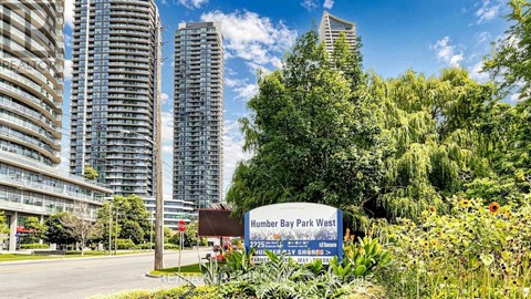 A sign for Humber Bay Park West stands in front of a row of tall buildings.
